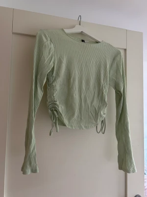 Mintgröntröja  - Mintgrön tröja med snörning på sidorna. I väldigt bra skick🩷