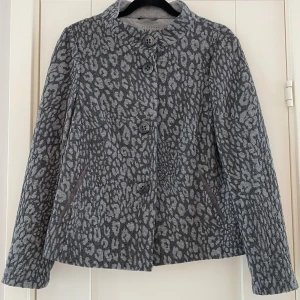 Grå mönstrad kofta från Bianca i strl 42 - Grå mönstrad kofta från Bianca i strl 42.  Sparsamt använd och i fint begagnat skick.  Mått Över bröstet: ca 54 cm Längd från axeln och ner: ca 59 cm  Bomull, polyester, viskos och elastan 