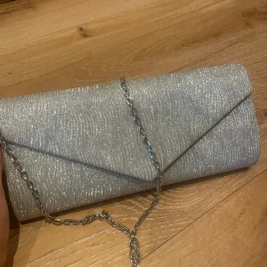 Clutch  - Silvrig Clutch från ”Mascara”, går att använda både med och utan axelkedjan. Nypris 550kr säljer för 200kr + frakt, använd endast en gång. En perfekt balväska!🥂