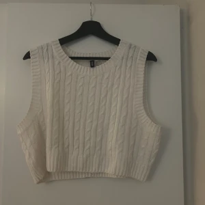 Stickad väst  - Säljer denna vita väst från H&M då den aldrig kommit till användning. Är helt oanvänd och i bra skick. Den är i storlek L. Den är croppad så lite kortare så skulle säga att det passar storlek S/M/L beroende på hur du vill att den ska sitta😊