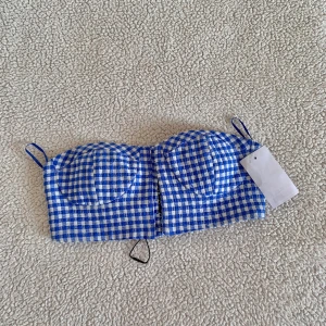 ZARA ginghamrutig crop top / balconette bustier  - Otroligt fin blå gingham rutig bustier topp i balconette modell från ZARA. Ny med tags kvar, utan anmärkningar. Knäpps där fram med kabinhakar. Storlek XS och passar någon med 75B-80B.