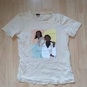 En t-shirt med tryck på tre tjejer. Den är från gina och i xs 💗