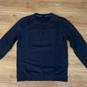 Hugo Boss sweatshirt - Säljer denna feta Hugo boss tröja i storlek M, grymt bra skick utan några defekter alls! Fin marinblå färg så passar utmärkt nu till sommaren, nypris 1350 men säljer den för 379! Kom PM vid fler frågor eller bilder på tröjan