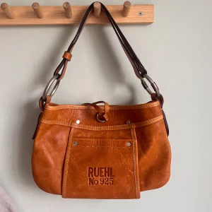 Väska - Söt väska köpt secondhand men aldrig använd, lapp är kvar. Ganska säker på att det är äkta läder. Från märket Ruehl New York