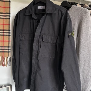 Stone island overshirt svart - Säljer denna sjukt snygga Stone island overshirten. Storlek S, men sitter något stort imo. Overshirten är i toppskick och har bara använts ett fåtal gånger. CLG koden på tredje bilden bekräftar äktheten! Bara att skriva vid frågor eller fler bilder!