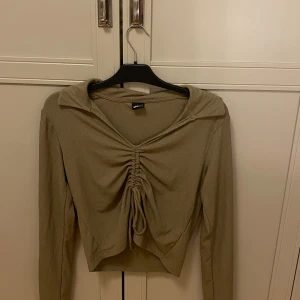 Långärmad Topp - Super fin topp. Den har ett knyte/resår i midjan, den har även en liten krage och är i ribbat material. Använd fåtal gånger❣️.