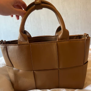 Brun Handväska - Brun handväska, axelrem finns. Från Nelly, använd några enstaka gånger. 🤎Rymmer jättemycket! Tryck inte på köp, kontakta mig! Samfrakar vid flera köp🫶🏼