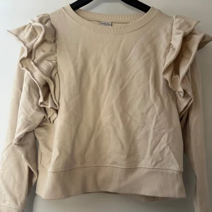tröja med volang - beige tröja med volang från ullared/gekås i storlek xs, väldigt fin tröja med volangkanter, säljer då den är lite för kort för mig! använd fåtal gånger, inga tecken på användning. skriv för fler bilder, köparen står för frakten 