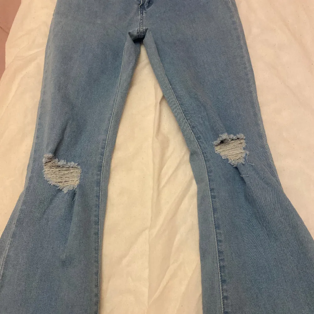 Utsvängda jeans med splitt och hål på knät. Små i storleken . Jeans & Byxor.
