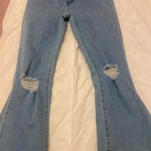 Utsvängda jeans med splitt och hål på knät. Små i storleken 