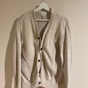Cardigan/kofta beige från H&M  - Stillig cardigan i storlek S från H&M. Tröjan säljs inte längre från butiken. Koftan är i bra skick, är varm med ett snyggt material. 