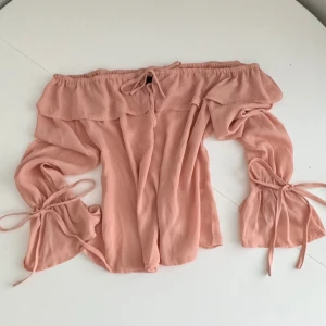 Coquette off shoulder blus - En jätte fin off shoulder blus med rosetter som man kan knyta vid ärmarna och framtill. Använd 1-2 gånger och är i fin skick. Lite genomskinlig. Skulle säga färgen är mer i verkligheten som den sista bilden. Lite gammelrosa. 