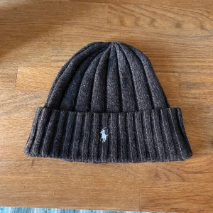 Grå Polo Ralph Lauren mössa, one size - Stilren Ralph Lauren mössa i skön ullblandning, passar till både våren och hösten! I nästintill nyskick, använd ett fåtal gånger. Kan mötas i Sthlm!