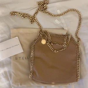 Stella McCartney väska tiny guldkedja  - Världens finaste väska från Stella McCartney, tyvärr en missfärgning på baksidan (kom privat för bilder) därav pris. Äkthetsbevis samt dustbag medföljer, nypris på denna är runt 8500, ❤️