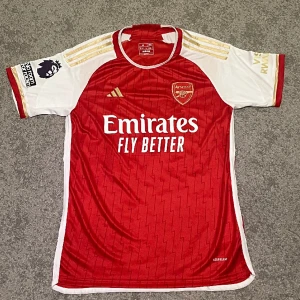 Arsenal hemmatröja 23/24 - En Arsenal tröja från denna säsong med Rice 41 på baksidan med Premier League patch på högerarmen. Den har mest legat i garderoben och inte används. Därmed är den i perfekt skick. Pris kan diskuteras.
