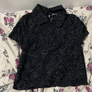 Kortärmad tröja med krage - Svart kortärmad tröja med krage och ett fint mönster.  