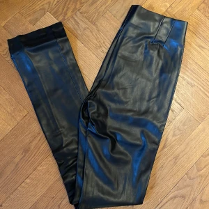 Faux läderbyxor från zara, oanvända!  - Helt nya byxor i läderimitation från zara, går inte att få tag i längre. Skitsnygga på med en slits nertill benen med dragkedja, stretchiga! Passformen är tight/flare. Aldrig använda så därför säljer jag dom☺️ 