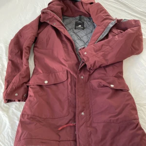 Vinterjacka - Vinröd vinterjacka, 100% vattentät, Didriksson, en liten reva (ca 5 mm) på baksidan av jackan. 