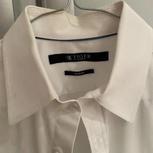 Vit skjorta Tiger of Sweden dubbel manschett storlek 38 - Vit skjorta från Tiger of Sweden  Ärmar med dubbel manschett Mycket fint skick, använd enbart enstaka gång! Skjortan tvättad och pressad på kemtvätt inför försäljningen  Storlek 38 slim fit (38cm bred och 73cm lång) 100% bomull