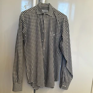 Rutig skjorta från the shirt factory  - Rutig skjorta från the shirt factory  Mycket fint skick, använd enbart enstaka gång! Skjortan tvättad och pressad på kemtvätt inför försäljningen  Storlek 39 tailored fit (42cm bred och 73cm lång) 100% bomull