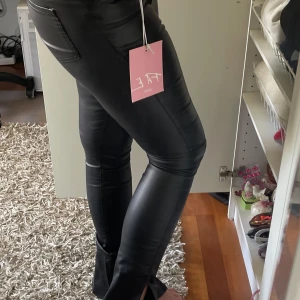 Skinnbyxor med slits  - Jättesnygga skinnbyxor med slits från asos, aldrig använda och med lappar kvar. Tyvärr försmå för mig, storlek UK 10. Högmidjade, utsvängda ben och slits. Nypris 699:- från märker Fae