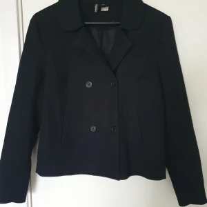 Svart kavaj/jacka - Kortare model, går ungefär till höften. Knappt använd.