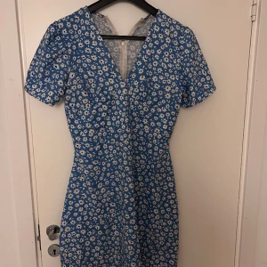 Blomklänning  - En jättesöt blå blommig klänning. Den är använd men skicket ser ändå bra ut. Den sitter bra i stoleken. 