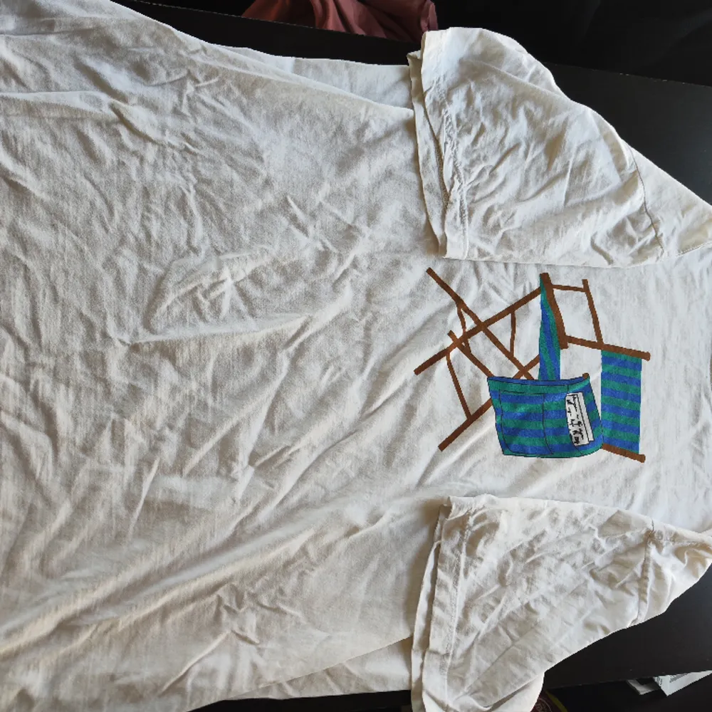 Vit t-shirt med tryck av en solstol, köpt på Second Hand, storlek XXL, tajt/liten krage men bekväm. Använt rätt så mycket men i bra skick, köparen får betala frakten. Skicka ett pm om du undrar något! :)). T-shirts.