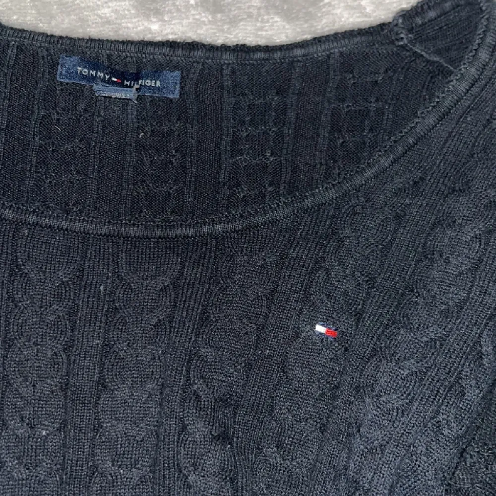 Mörkblå kabelstickad tröja med mian detaljer längst ner från tommyhilfiger. Stickat.