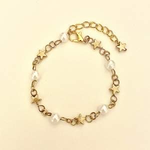 Handgjort guldfärgad armband med guldiga stjärn pärlor och vita runda. Tryck på köp nu om du vill köpa🥰