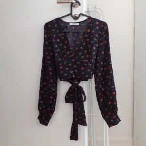 blus med knytband - en vacker blus som man knyter där bak! bara använd typ 2 gånger 💌 har ett väldigt fint mönster på sig i form av små röda bär