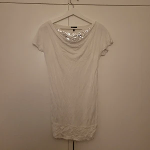 Vit fintröja med silvriga paljetter - Denna vita tröjan kan man både ha i en längre modell med tights till eller dra upp den och ha som en kortare modell. Mycket fin tröja i fint skick!