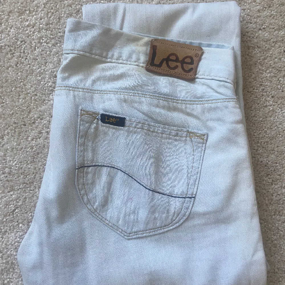 Ett par vita/väldigt ljusblåa lågmidjade jeans från Lee. Har lite fläckar men inget som märks av.  Midjemått: 41 cm Ytterbenslängd: 102 cm Innerbenslängd: 84 cm. Jeans & Byxor.