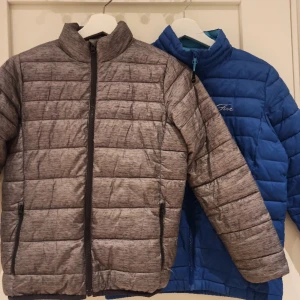 Dunjackor - Två super fina dunjackor i blått och grått.  Den blåa är i storlek 146/152 och gråa i storlek 140.  Perfekta att växa in i! Jag kan även sälja dem separat vid intresse, kontakta mig innan du köper i så fall.  50 kr styck eller 80 kr för båda två🌟