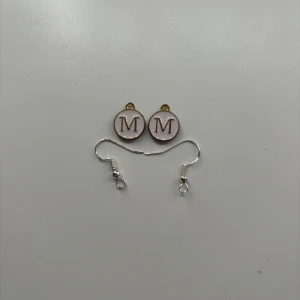 M berlock som örhängen  - Dessa är örhängen som jag gör själv. Ni bestämmer själva vilken färger ni vill ha. Men det finns bara de färger som är med på bilderna. Dessa är aldrig använda. Skriv till mig om du undrar något. OBS! När du köper denna kommer du endast köpa ett par!