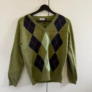 En olivgrön stickad tröja med argyle mönster från Emmiol.  Storleken är M  