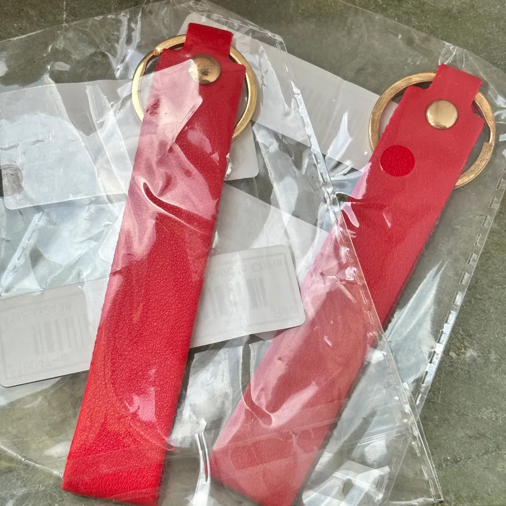 2 st röda nyckelringar, fortfarande kvar i förpackningen då de inte har kommit till användning ännu. Pu läder! . Accessoarer.