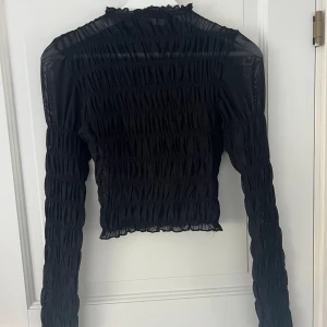 Svart Meshtopp - Svart topp i mesh från Na-Kd i storlek M. Snygg lite kortare festtopp i fin kvalitet! Köparen står för frakten🥰