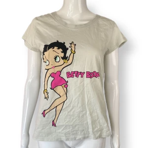 Betty Boop - I fint skick, 8/10. Dockan använder storlek XS. Behöver strykas. MÅTT: Axel till axel 38cm, ärmlängd 11cm, armhåla till armhåla 46cm & längd 61cm