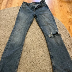 Jeans med slitning - Blåa jeans med slitning på ena knät💗 från Gina i storlek 34