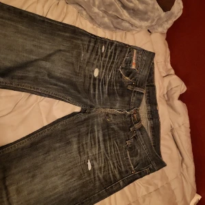 Disel jeans - Låg/medel midjade jeans från disel, ena framfickan är trasig på insidan. As snygga och raka i passformen. Har en mer muted ton på jeans tyget