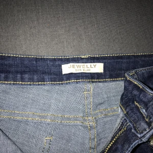 Jeans - Blå byxa med diamanter och pärlor på fickan på framsidan. Den går att stretchig 