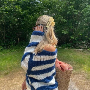 Randig stickad tröja - En mysig och bekväm stickad tröja med breda horisontella ränder i blått och vitt. Tröjan har långa ärmar och en lös passform, perfekt för kyligare dagar.