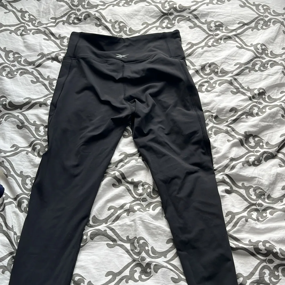 Ett par svarta leggings från Reebok med Speedwick-teknologi. De har en hög midja och är tillverkade i ett syntetmaterial som är designat för att transportera bort fukt och hålla dig torr under träning.. Jeans & Byxor.