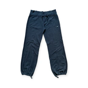 Nike svart pösiga mjukisbyxor - Snygga svarta träningsbyxor/mjukisbyxor. På vänster ben sitter en vit Nike-logga. Byxorna har en ficka baktill med en vit text över där det står "STUDIO". Sparsamt använda, I fint skick!