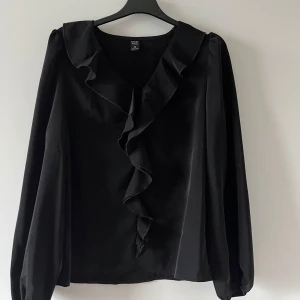 Svart blus med volang  - RESERVERAD! !! 