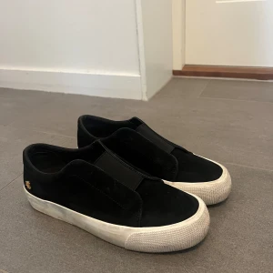 Svarta skor med vit sula - Ett par svarta Ralph Lauren sneakers med vitt sula. Använt Max 5 gånger så inte så välanvända.  Pris kan absolut diskuteras!