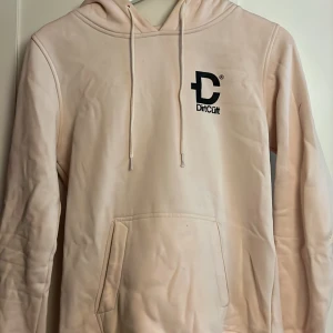 Hoodie - En ljus rosa dirtcült hoodie med litet tryck på sidan och ett stort tryck bak på ryggen! Tröjan är i storlek M men jag skulle säga att den sitter som XS/S den är väldigt liten i storleken. 