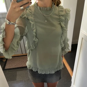 Grön volangblus - Grön blus med volanger från H&M i storlek 38. Passar Soch M. Fint skick. Använd gärna köp nu!