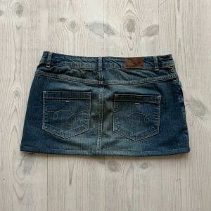 Lågmidjad jeanskjol  - Blå lågmidjad jeanskjol från More & More i storlek 38 som jag har sytt upp från en lite längre kjol. Fint skick. Tvärs över midjan är det 42 cm och längs med sidan är det 31 cm. Använd gärna köp nu!